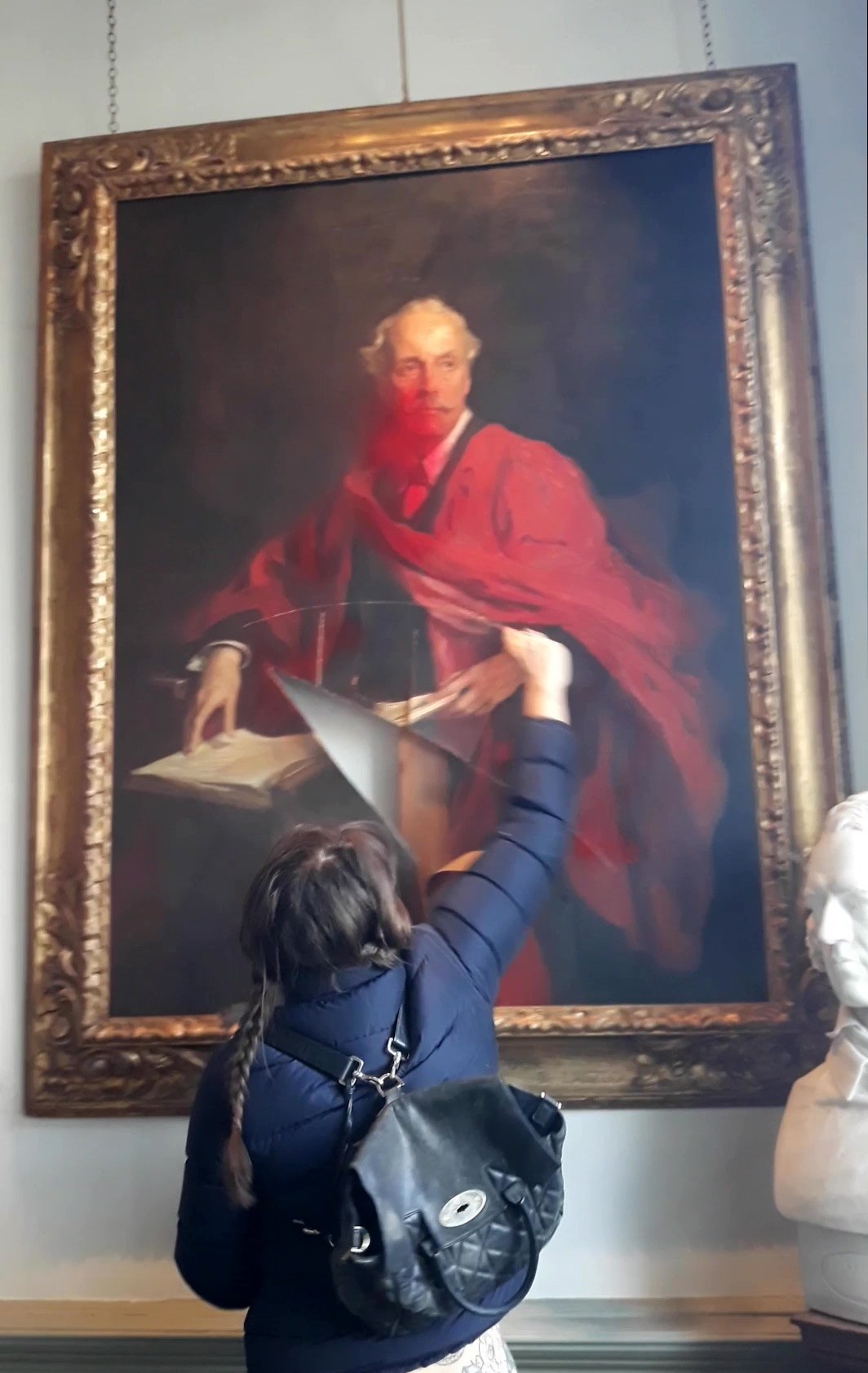 An activist slashes a painting of former UK Foreign Secretary Lord Arthur James Balfour after spraying it with paint.