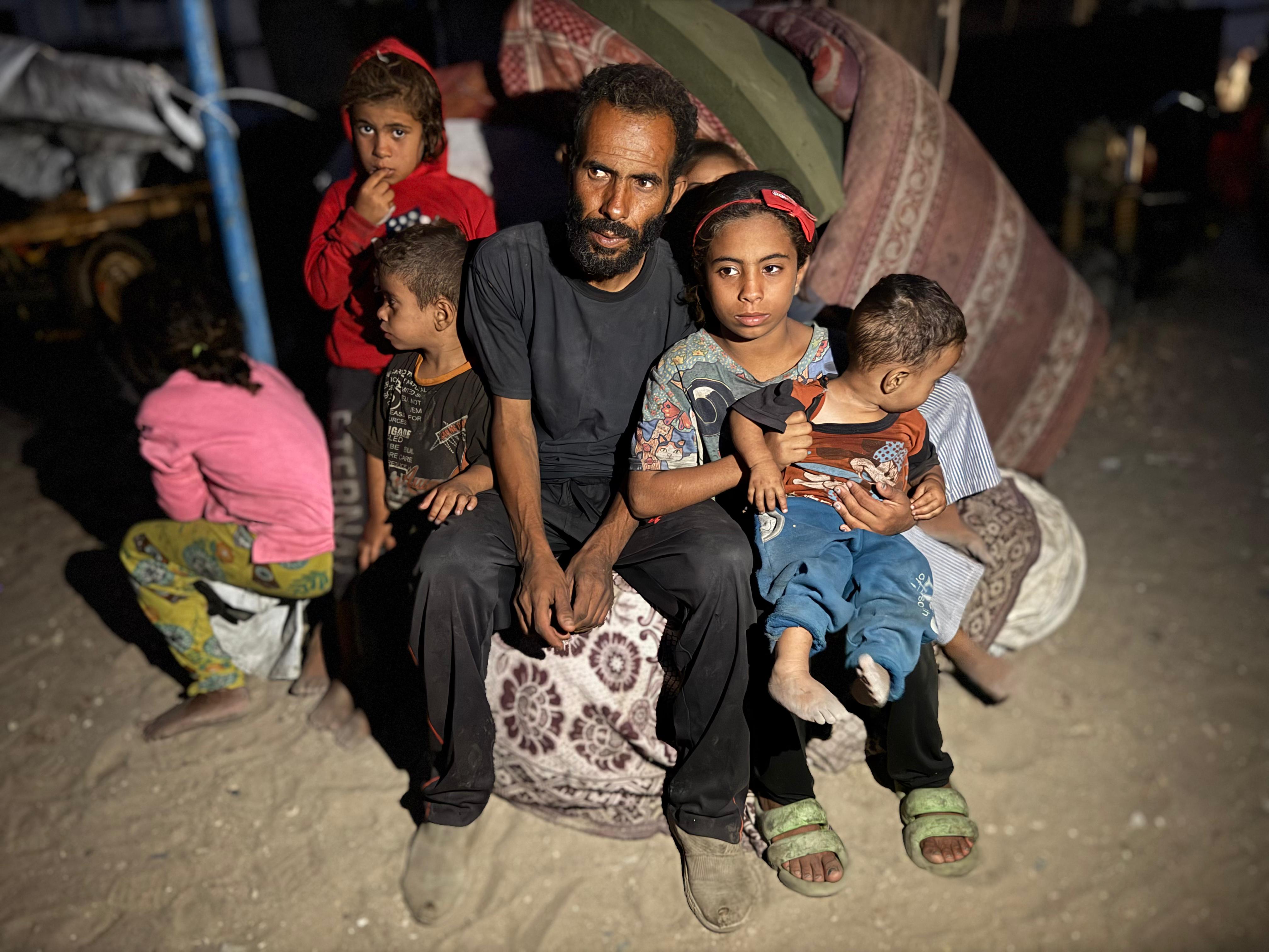 A Palestinian father and his seven children sit together outside their tent in Gaza.