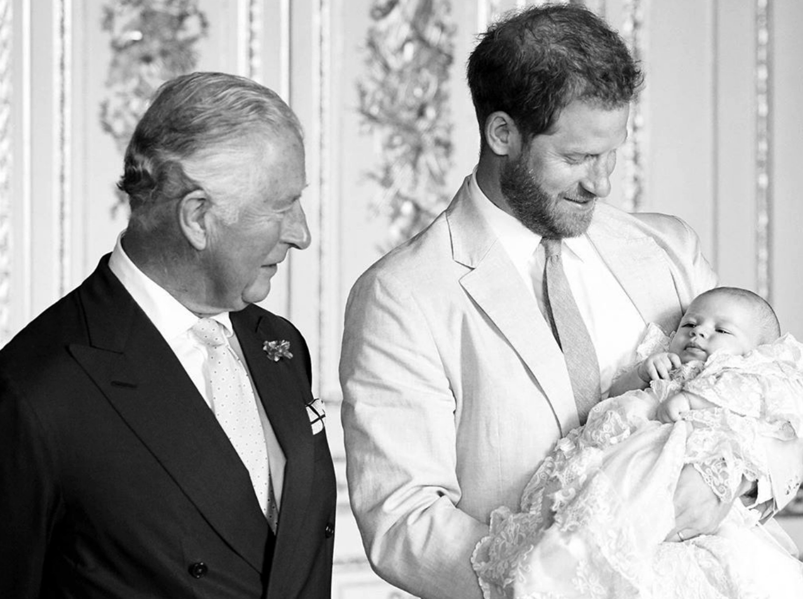 Black and white photo of Prince Charles, Prince Harry, and baby Archie.