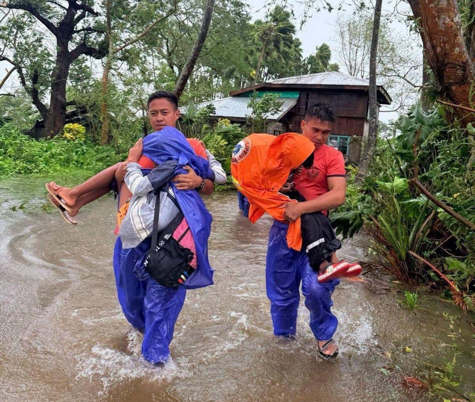 Philippine Coast Guard rescuers carry two people through floodwaters in Cagayan Province after Typhoon Ragasa.