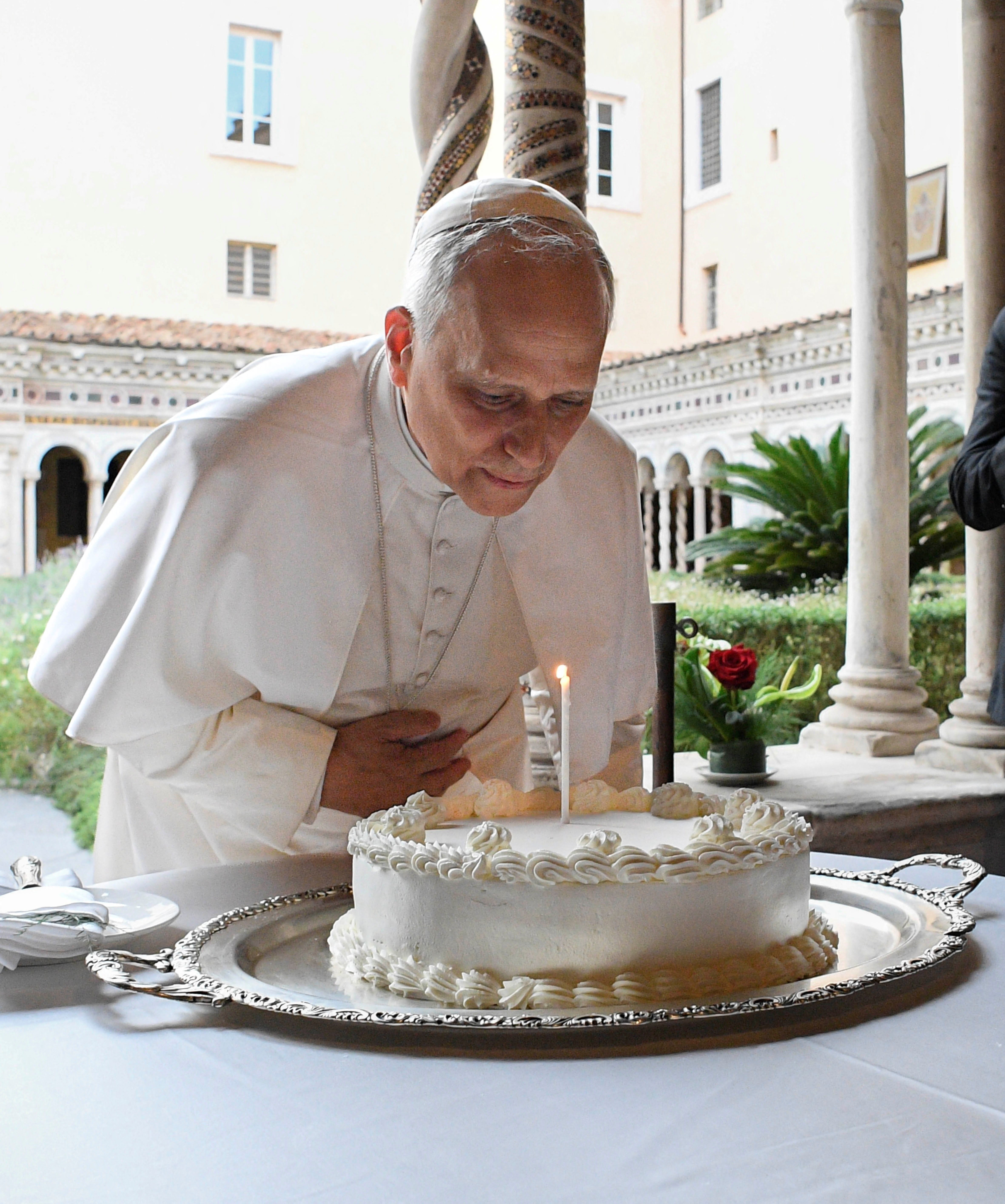 Pope Leo blowing out a candle on a birthday cake.