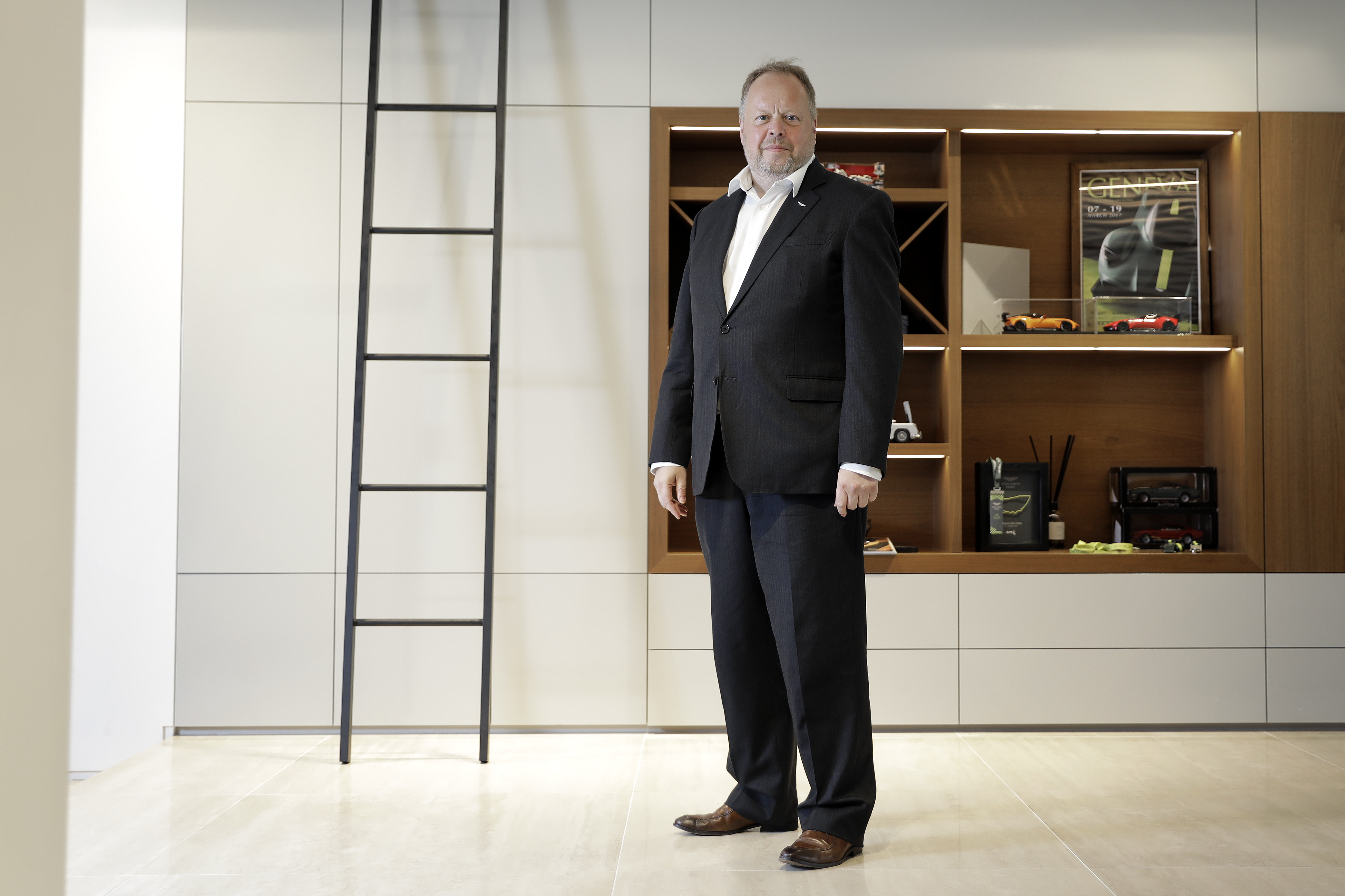 Andy Palmer, CEO of Aston Martin Lagonda, poses in a suit with a white collared shirt.