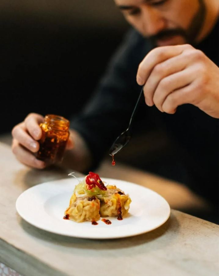 Chef Daniel Lee topping Siu Mai with crispy chili oil.