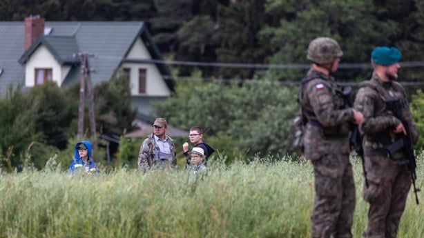 A local family stands in their field to watch as the Polish and Lithuanian president address a press conference following a joint visit of the NATO Multinational Division North East mobile command center near Szypliszki village, located in the so-called Suwalki Gap - an 80-kilometer stretch of the P