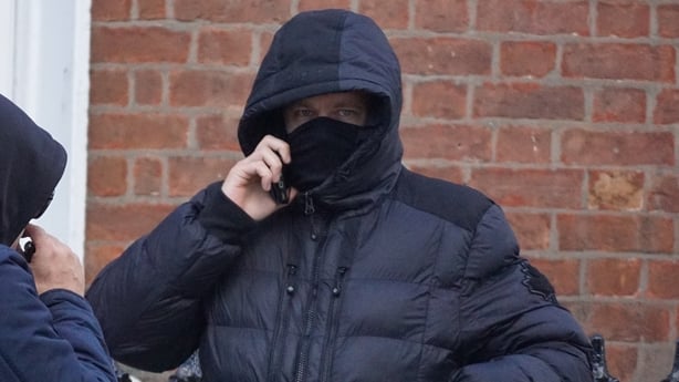 An image shows Paul Nolan with his hood up outside court