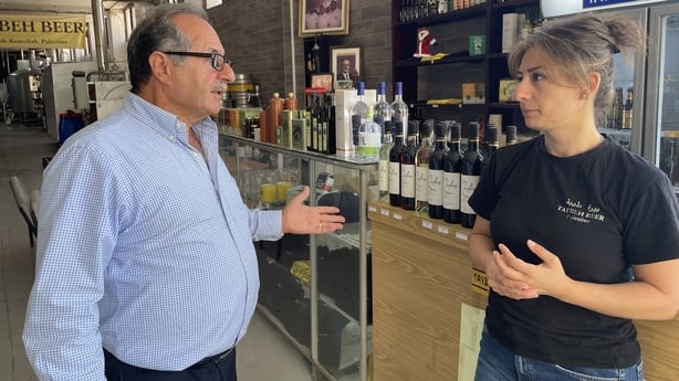 Madees Khoury and her father Nadim, owners of the Taybeh Brewing Company chat next to a counter with drinks on it