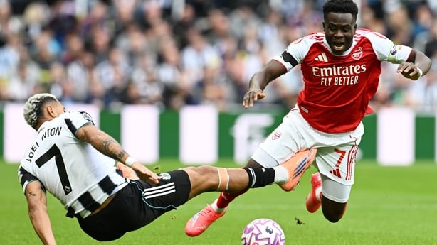 Bukayo Saka of Arsenal is tackled by Joelinton of Newcastle United during the Premier League match between Newcastle United and Arsenal at St James' Park on September 28, 2025 in Newcastle upon Tyne, England.