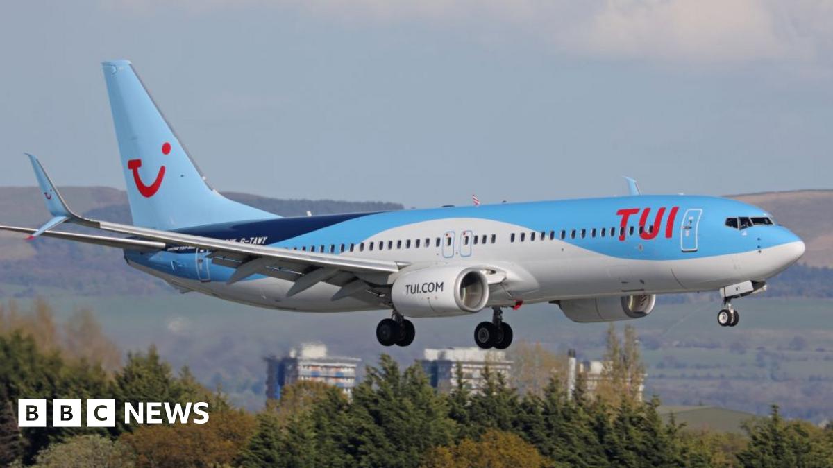 A Boeing 737 flying in the sky with a light blue, dark blue and white TUI livery