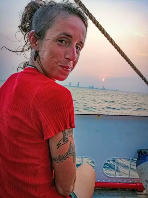 Matthias Berg/Klima Segler Giulia enjoying the spectacle of sailing past Miami skyline at sunset before the thunderstorm hit. She has dark hair tied back and is wearing a red top