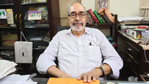 Jehangir Patel, wearing a white shirt, sits in his office at the Parsiana in Mumbai