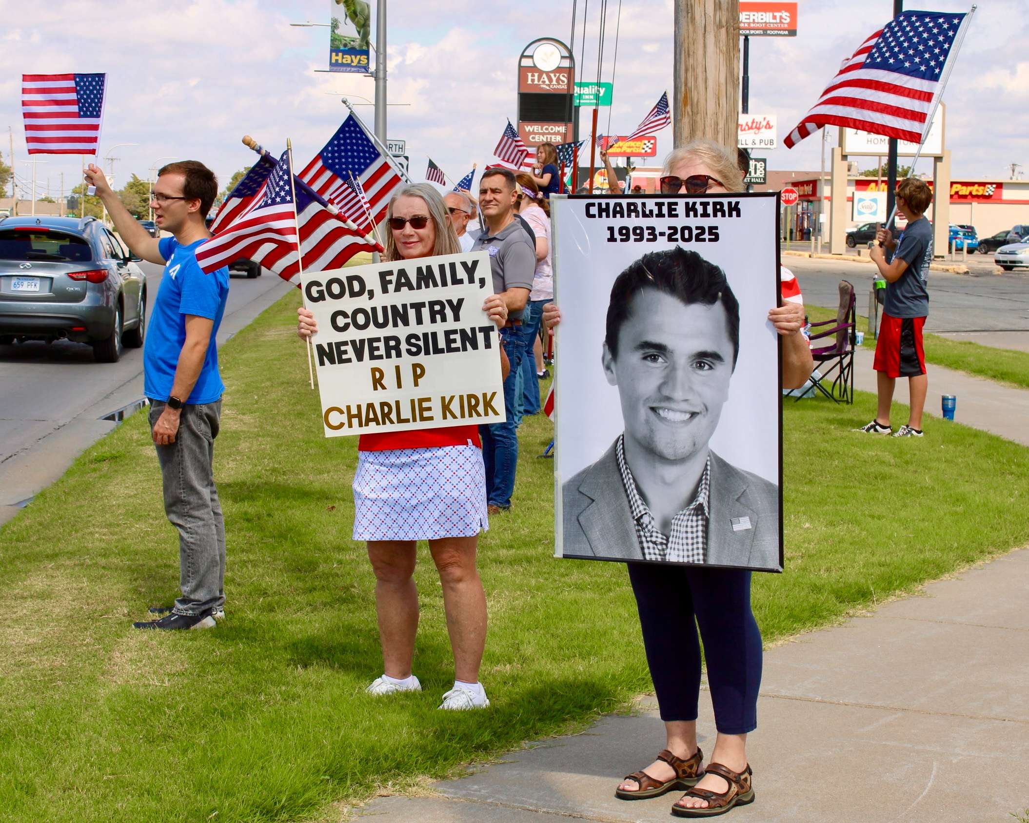 Hays residents with signs and flags on the corner of 27th and Vine. Photo by Tony Guerrero/Hays Post
