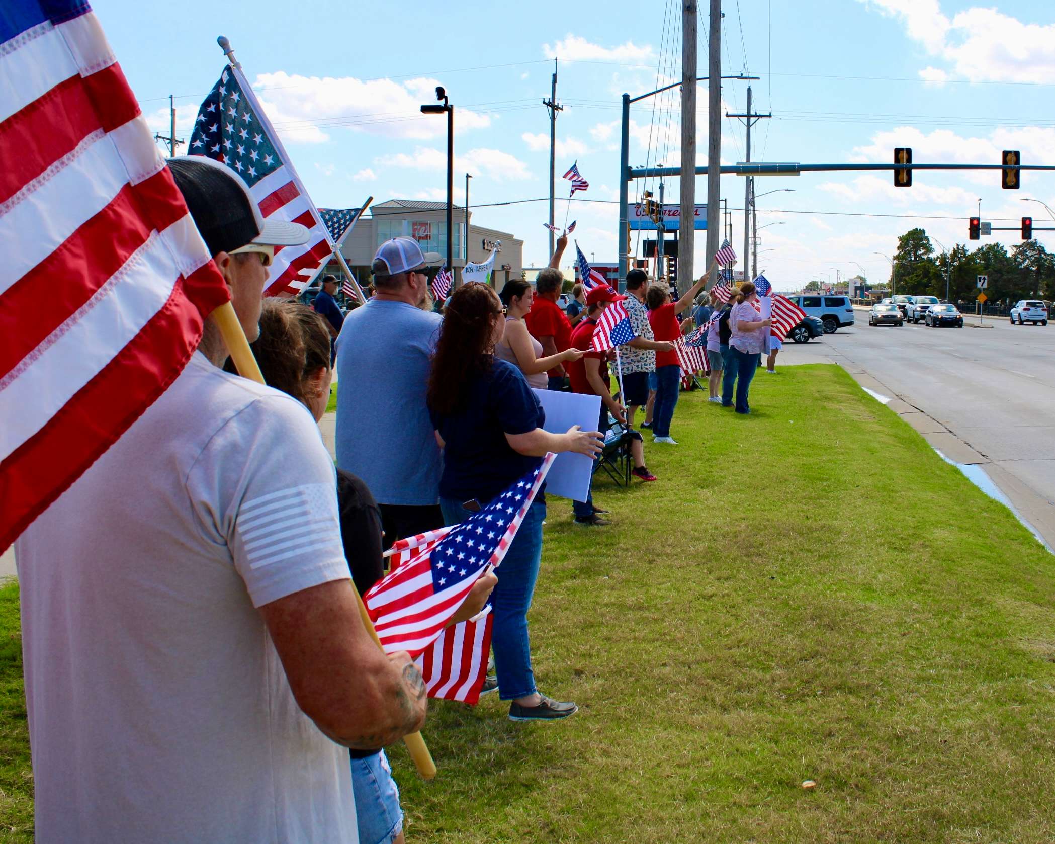 Attendees with the American flags, and signs on the corner of 27th and Vine in Hays. Photo by Tony Guerrero/Hays Post