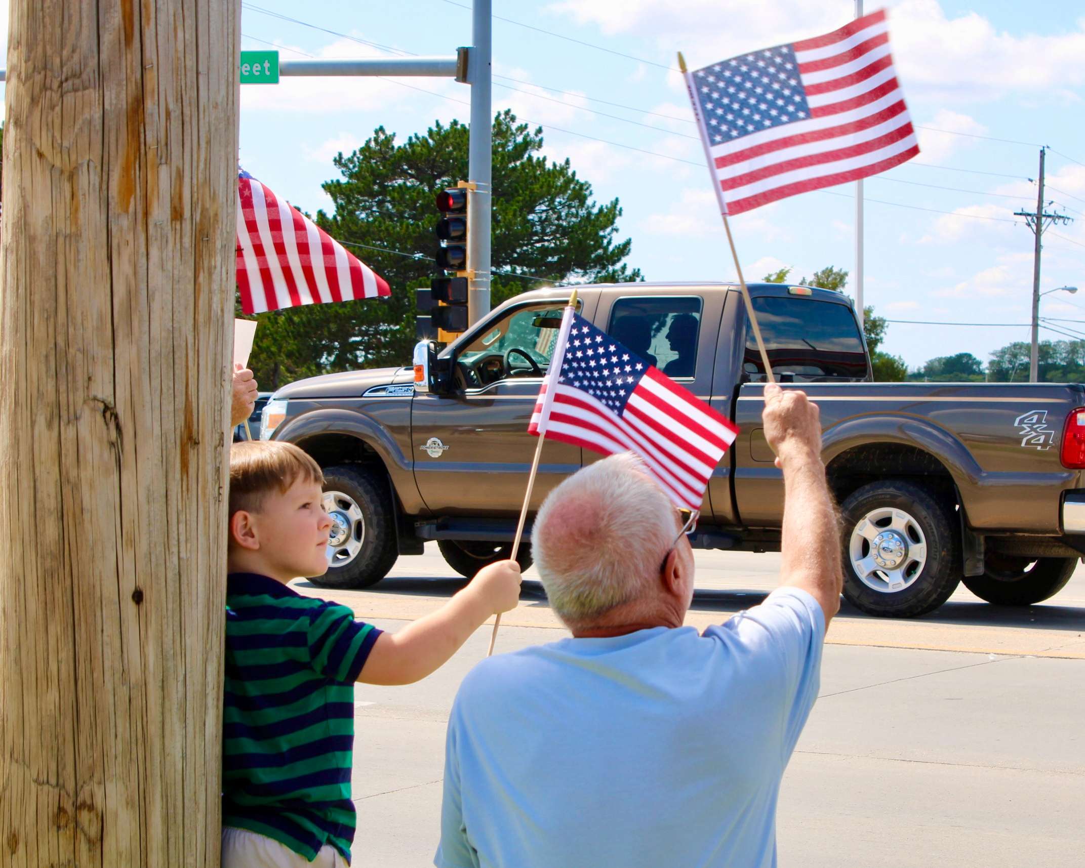 Attendees with American flags on the corner of 27th and Vine in Hays. Photo by Tony Guerrero/Hays Post
