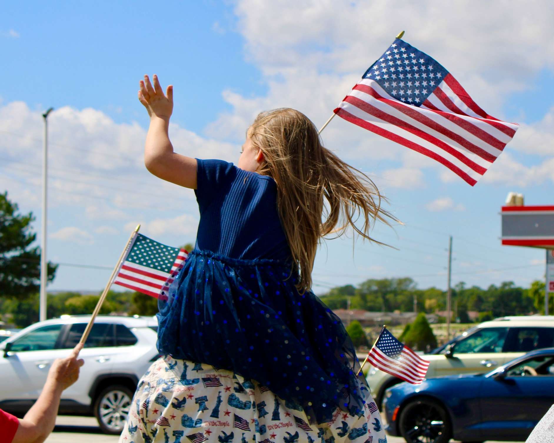 A little girl with an American flag, waving at cars passing by on the corner of 27th and Vine in Hays. Photo by Tony Guerrero/Hays Post