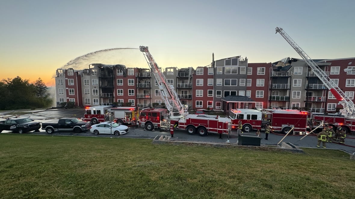 Fire trucks are shown in front of an apartment building.