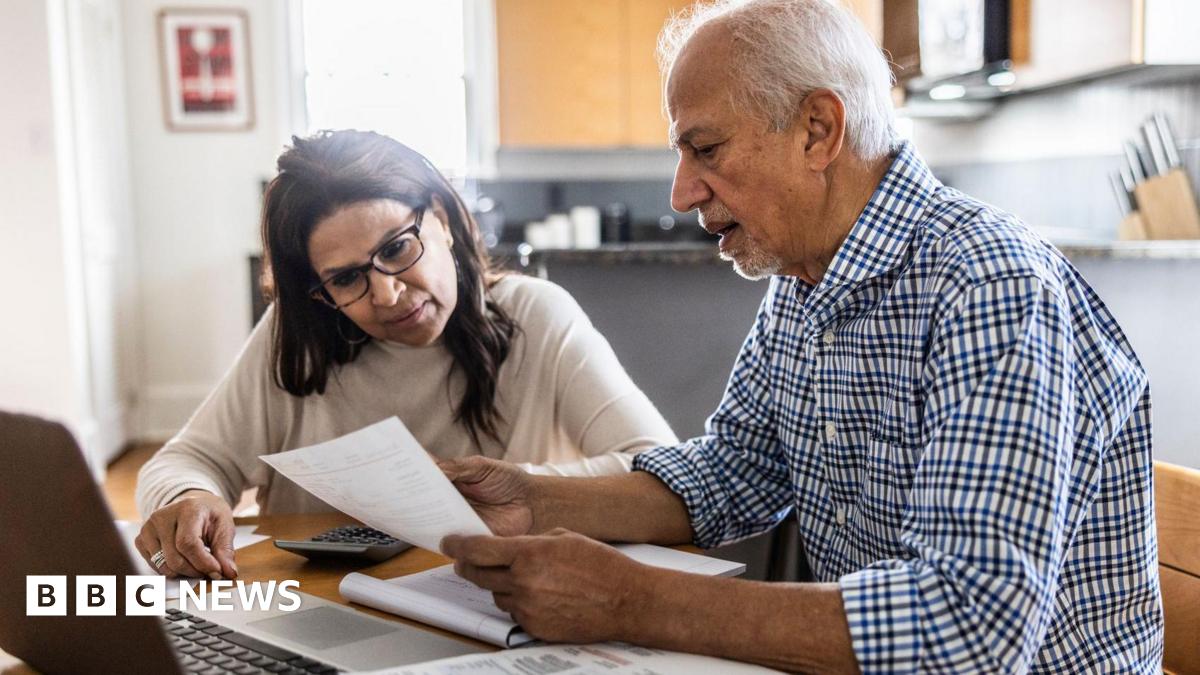 A man and a woman review paperwork at a kitchen table.
