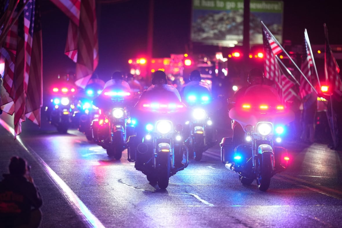A procession of police vehicles at night.