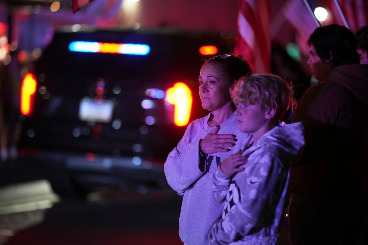 People look on during a police procession.