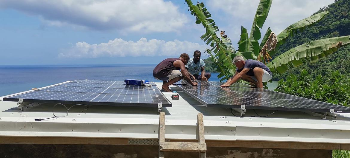 People in Vanuatu in the southwestern Pacific install solar panels on a roof.