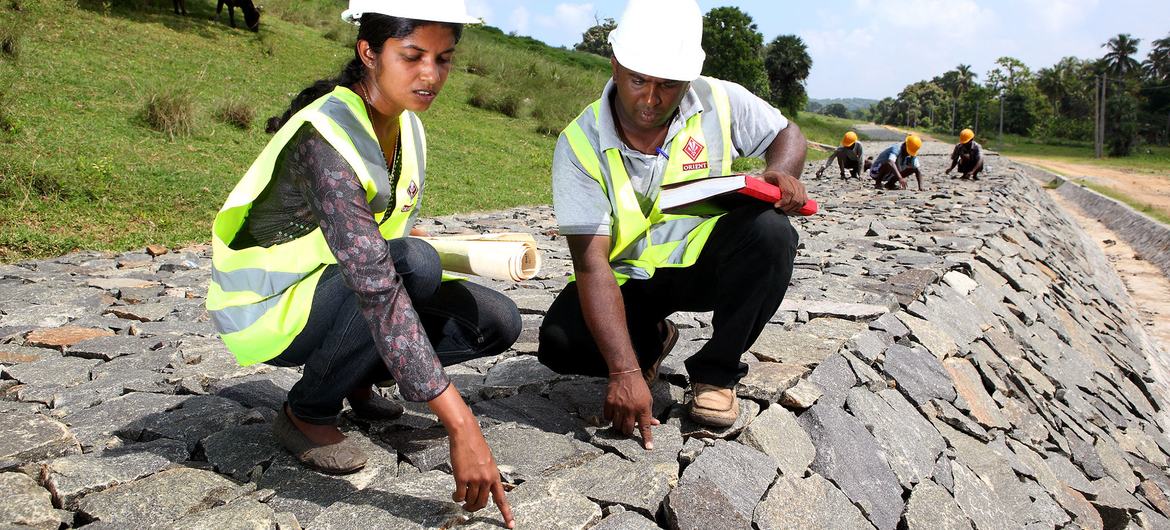 Working alongside her male team member, a woman employee checks the quality of work at a dam under construction in Sri Lanka.