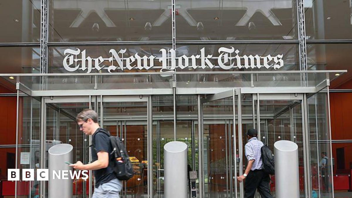 The New York Times building is seen on September 16, 2025 in New York City. The images features the logo of the newspaper, displayed atop the building's front doors, with people walking by.