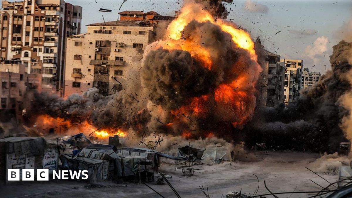 A huge ball of flame and black smoke fills the shot, as an air strike hits an urban centre in Gaza City.