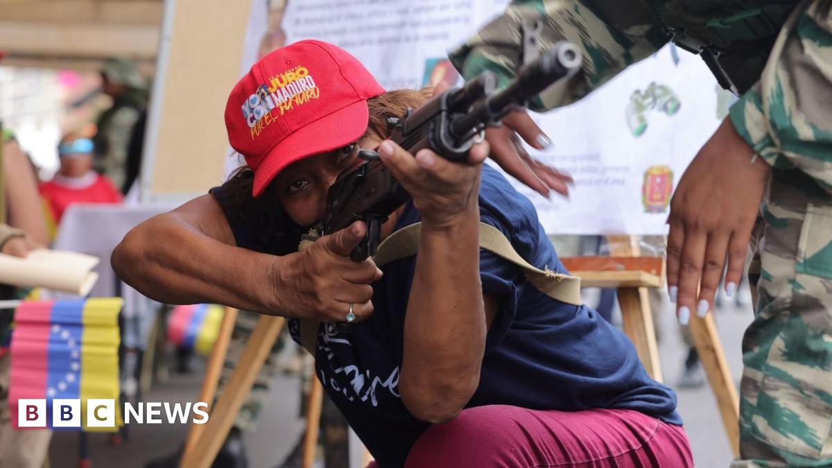 Edith Perales looks at the camera through a window. He is wearing a uniform in camouflage colours and a hat with the emblem of the militia. He has a grey moustache and greying temples.