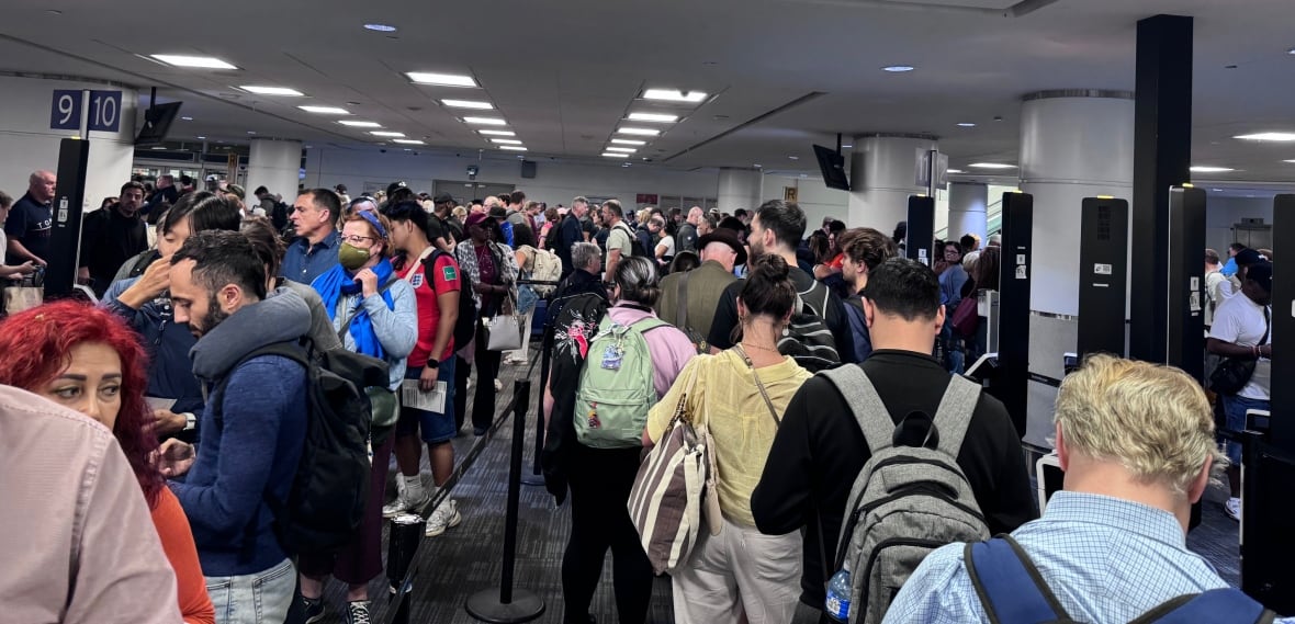 Travellers line-up in a crowded room.