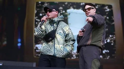 Getty Images Kneecap performing live at Glastonbury, wearing tracksuits and holding microphones