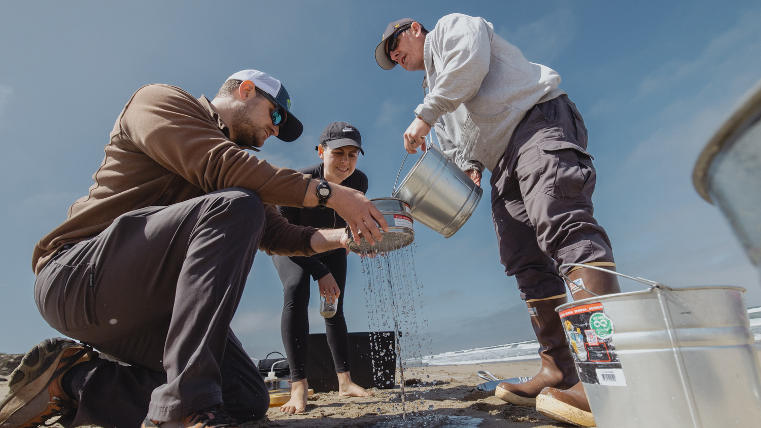 Image of Matthew Savoca, Monica Amador, and Chad King filtering sand and ocean water.