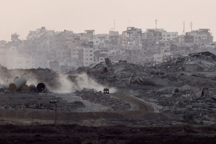 A vehicle travels past damage and debris in Gaza on Thursday.