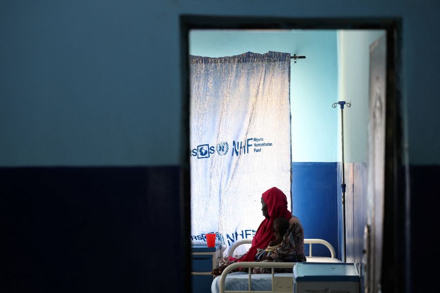 A woman and her malnourished child wait for care at the emergency ward of Dikwa Primary Health Center, where children are stabilized for severe malnutrition, following the reduction of USAID support, in Dikwa, Borno state, Nigeria, on August 27, 2025.