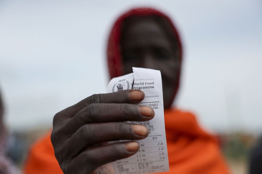 A beneficiary displays a food voucher after receiving support at a WFP distribution center in Dikwa, on August 27, 2025.