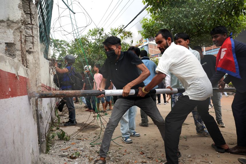 Demonstrators attempt to break an outer wall of the parliamentary complex in Kathmandu, Nepal, on Tuesday. Hundreds of people have been injured.