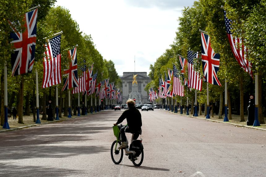 A man rides an e-bike across the road as American and British flags line The Mall in front of Buckingham Palace in London, on Tuesday.