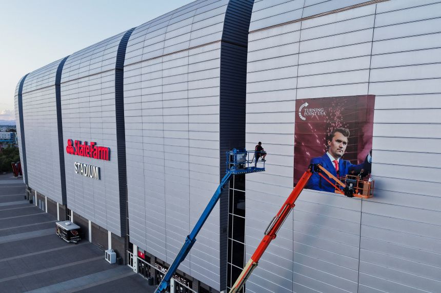 A drone view of workers installing a photo of slain conservative activist Charlie Kirk, ahead of a memorial service on September 21 at State Farm Stadium, in Glendale, Arizona.