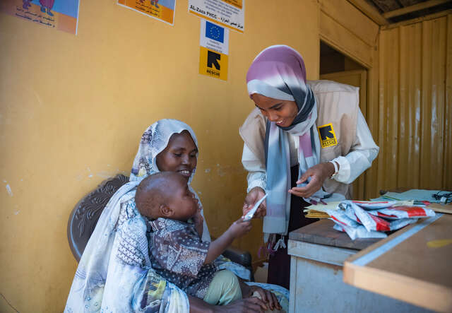 An IRC nutrition officer at the clinic gives Anwar his portion of therapeutic food as part of his malnutrition treatment. 