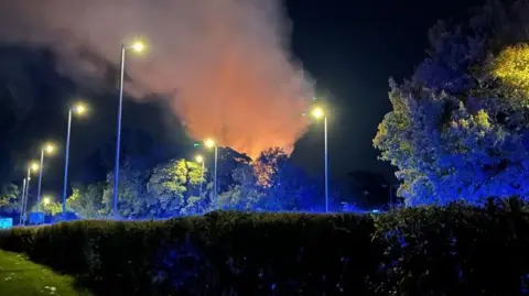 Orange smoke going up in night sky