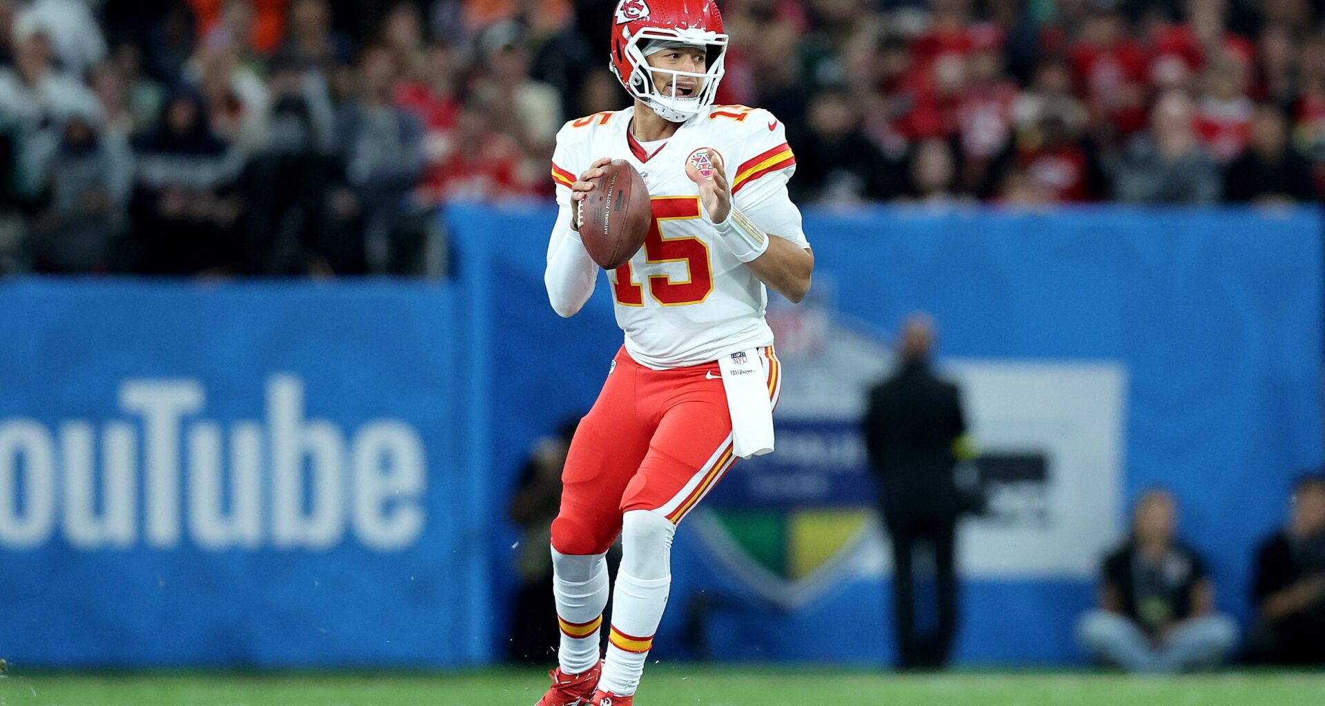 Patrick Mahomes holds the football and looks down the field.