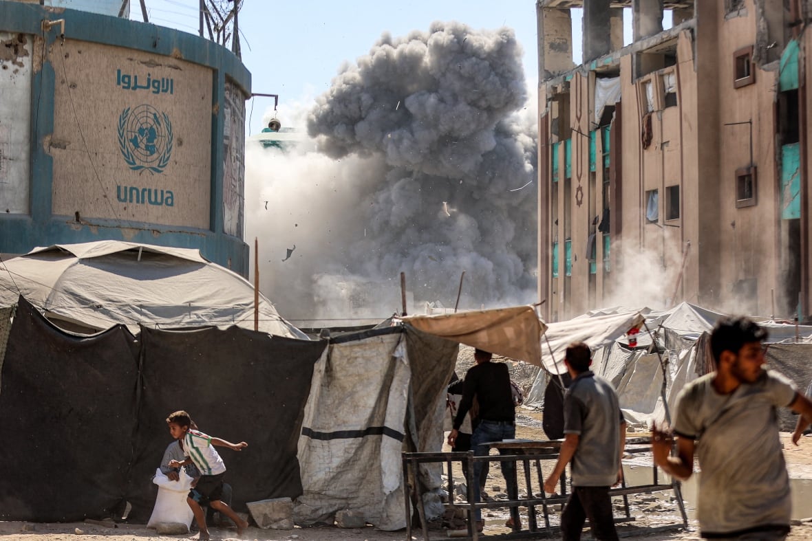 People run as smoke from an explosion erupts from a building.