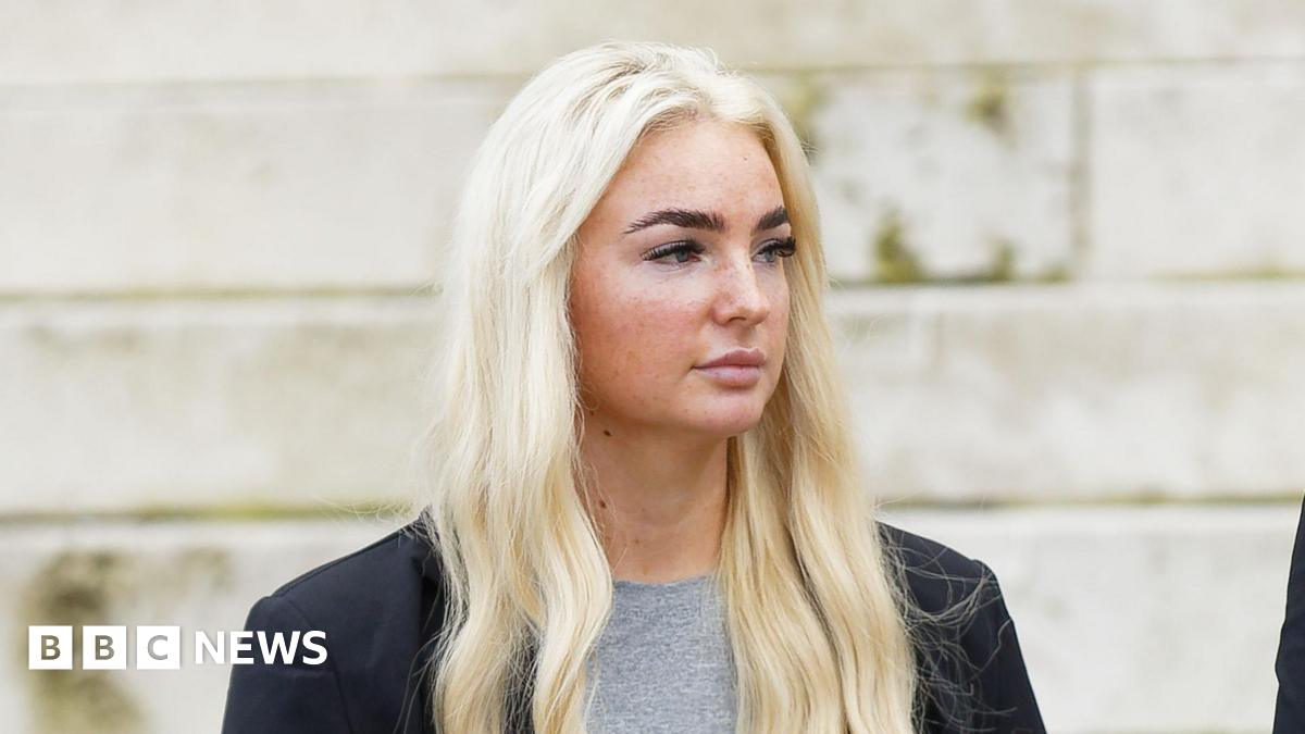 Close up of Megan looking away from the camera. She wears a grey t-shirt and a black blazer. Megan has long blonde hair and black eyelash extensions.