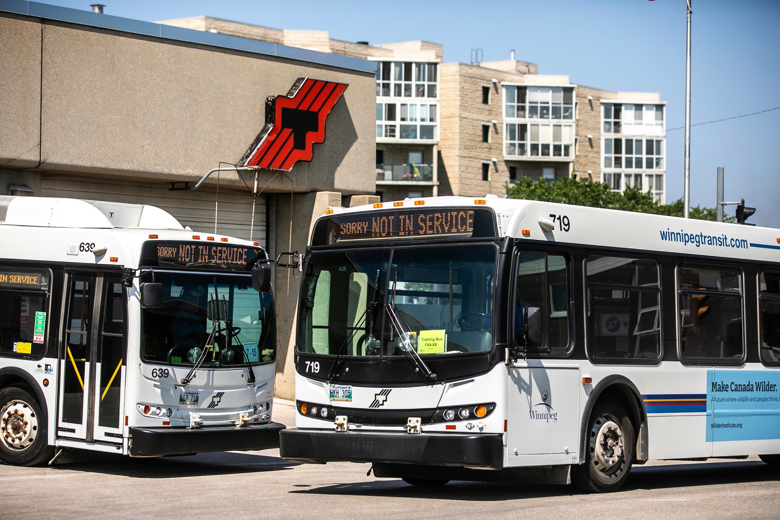 Two out-of-service Winnipeg Transit buses wait in the parking lot of the Winnipeg Transit garage