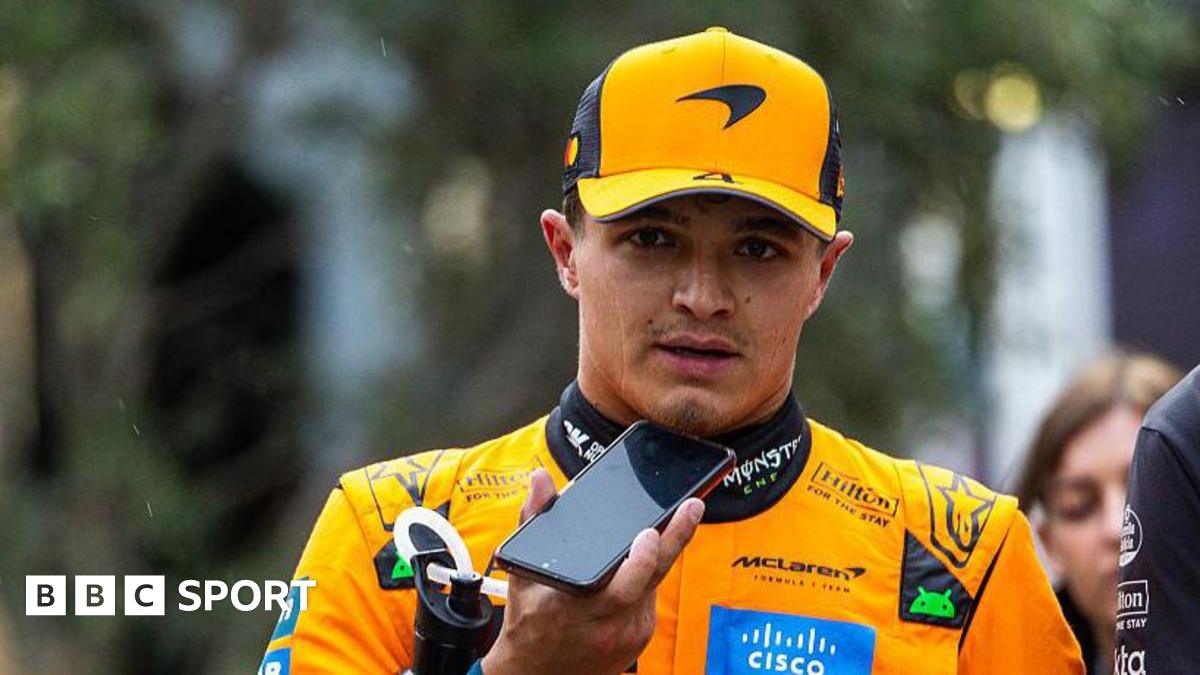 Lando Norris walking in his McLaren suit after qualifying in Baku and talking into a mobile phone