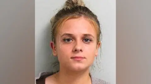 Metropolitan Police Custody image of Roksana Lecka. She is looking directly at the camera wearing a woollen type cardigan.