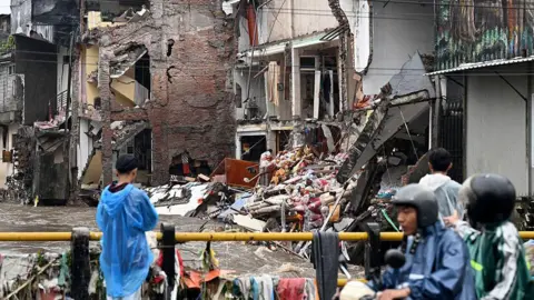 Getty Images View from a bridge showing a water-flooded street, with partially collapsed houses