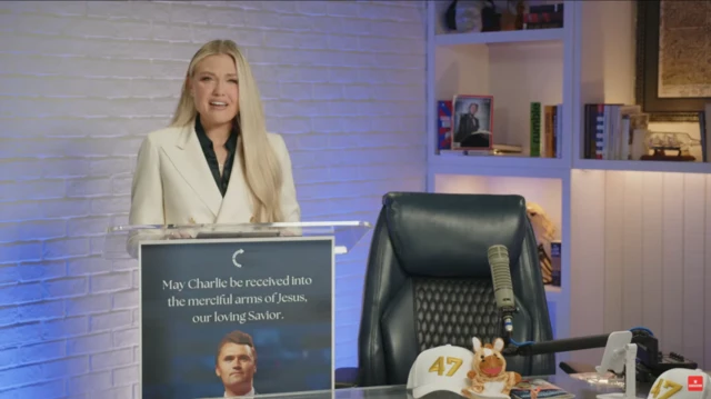 Erika Kirk speaking behind podium. In the front is a picture of Kirk on a blue background with the quote "May Charlie be received into the