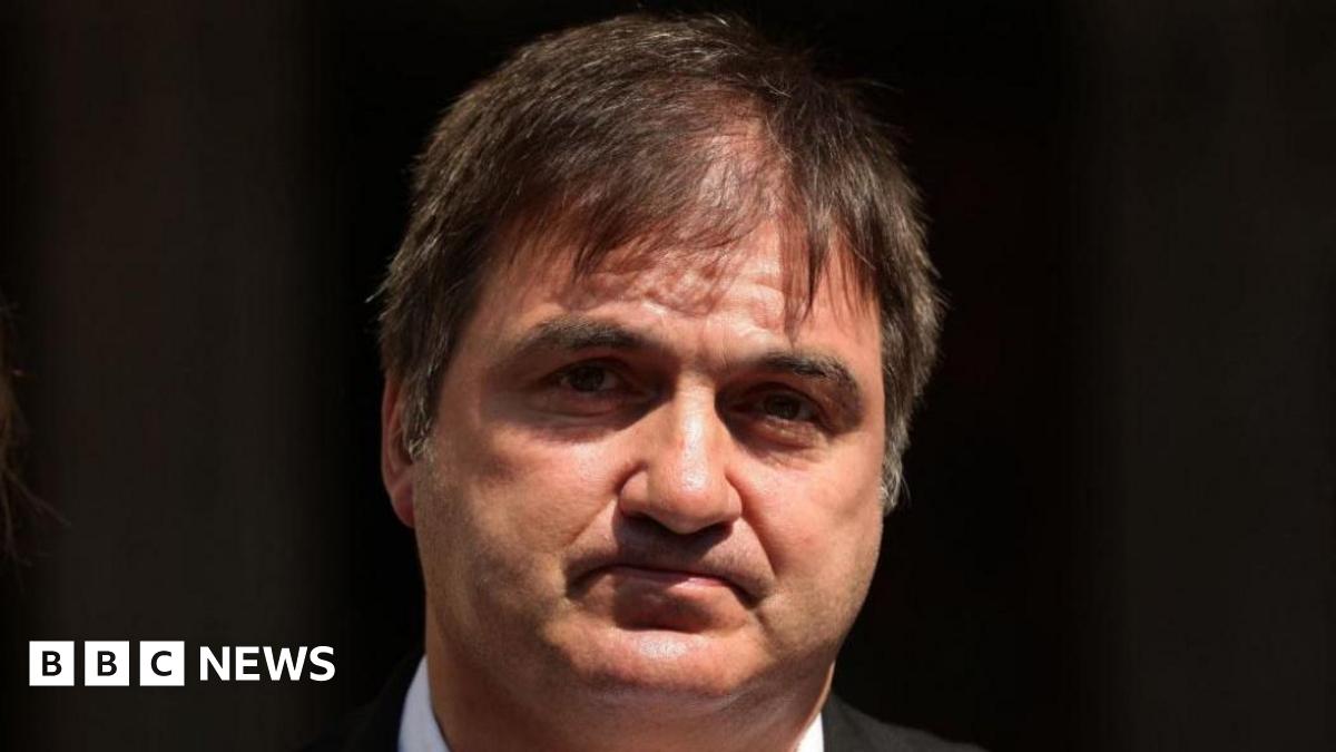 Barry George has dark hair and a white collared shirt