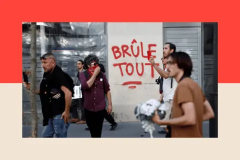 REUTERS/Benoit Tessier Protesters walk past the slogan "Burns everything" paint on a wall 