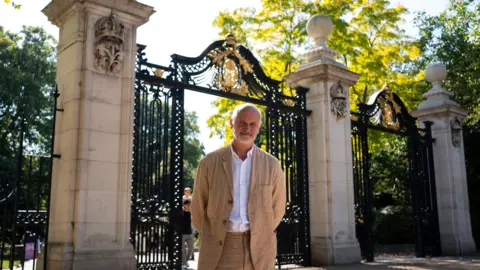PA Media Martin Jennings at Marlborough Gate, St James's Park. It is sunny outside and he wears a beige linen suit and is smiling with his hands held casually behind his back