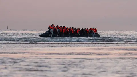 Getty Images Migrants sit on a dinghy as it prepares to sail into the English Channel on 10 July 2025 in Gravelines, France.